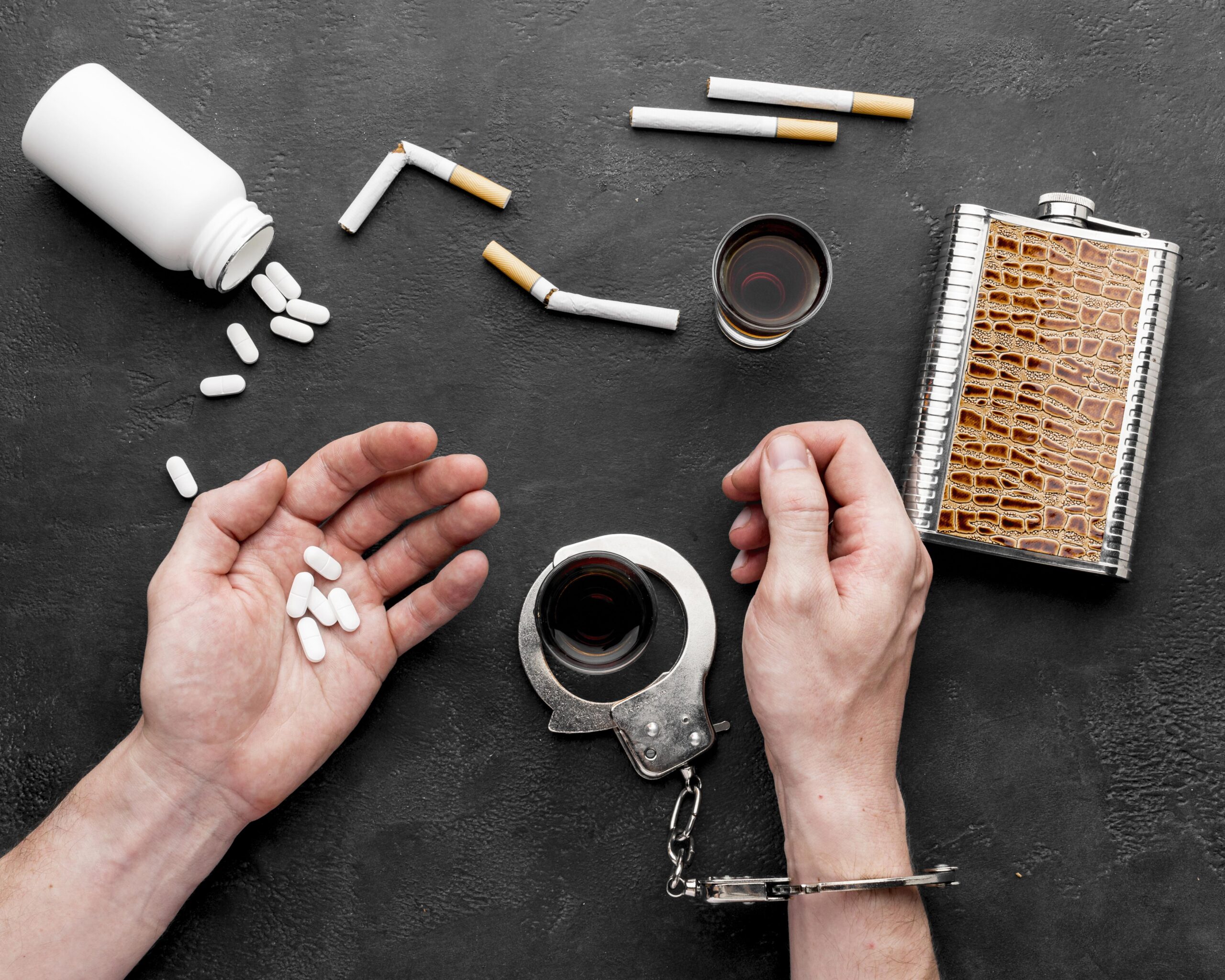 A person surrounded by alcohol, cigarettes, pills, symbolizing stress vices.